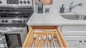 A kitchen with a stainless steel sink, a wooden drawer organizer with utensils, and a stove. - Private Apartment on River Ave. close to main st (Patchogue)