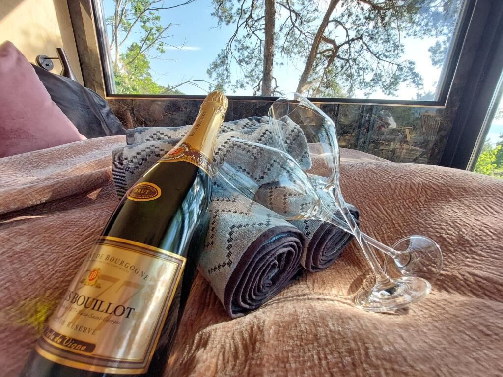 Een fles wijn, een glas en een patroonstof op een bed met uitzicht.