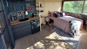 Una camera compatta con un letto, un comodino e una finestra vista alberi.