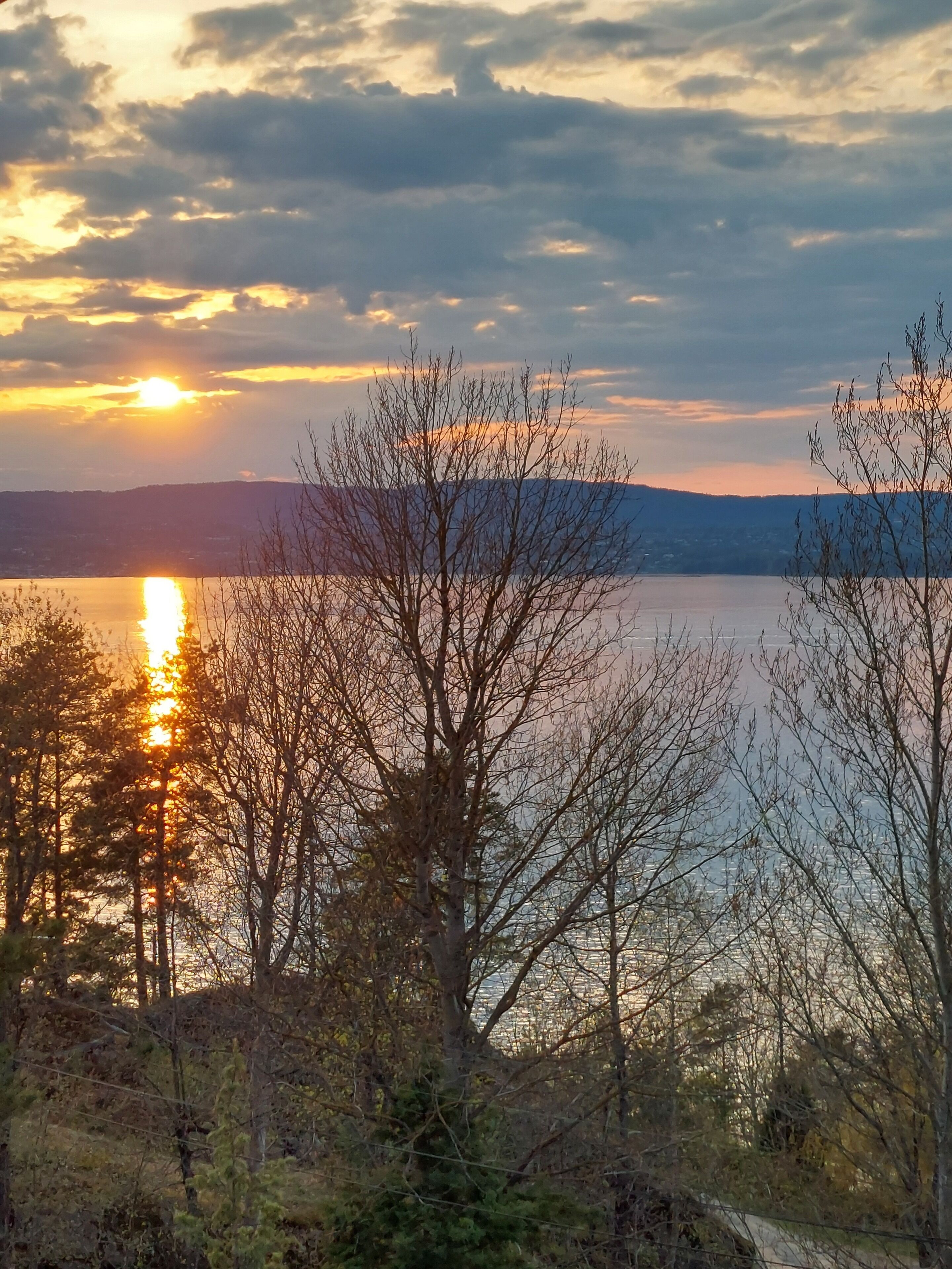 A sunset over a lake with trees in the foreground.