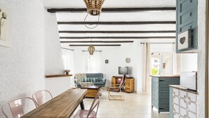 A spacious living area with a wooden dining table, chairs, a sofa, and a television. - WELCS APARTAMENTO 102 EMP con Piscina (Empuriabrava)