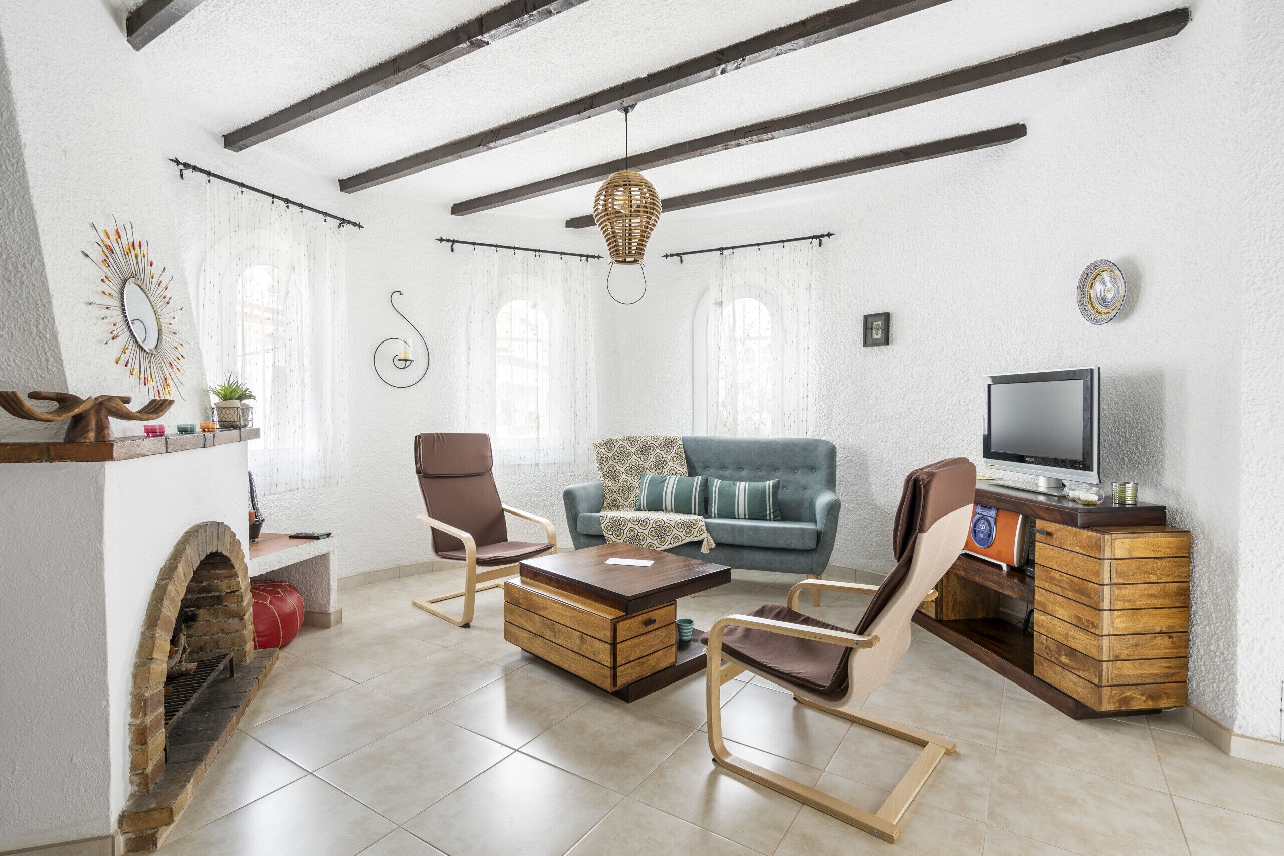 Ein Wohnzimmer mit Kamin, einem blauen Sofa, einem Holztisch und einem Fernseher auf einer Holzkommode.
