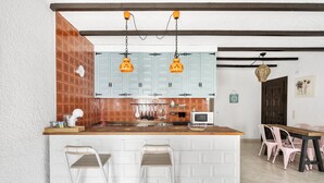 A kitchen with white cabinets, a wooden countertop, and two hanging orange pendant lights. - WELCS APARTAMENTO 102 EMP con Piscina (Empuriabrava)