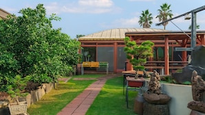 A well-maintained garden with a variety of plants, a clear pathway, and a building with large windows and a tiled roof. - Jeju Jeonwonsaenghwal Diorem Pension (Jeju City)