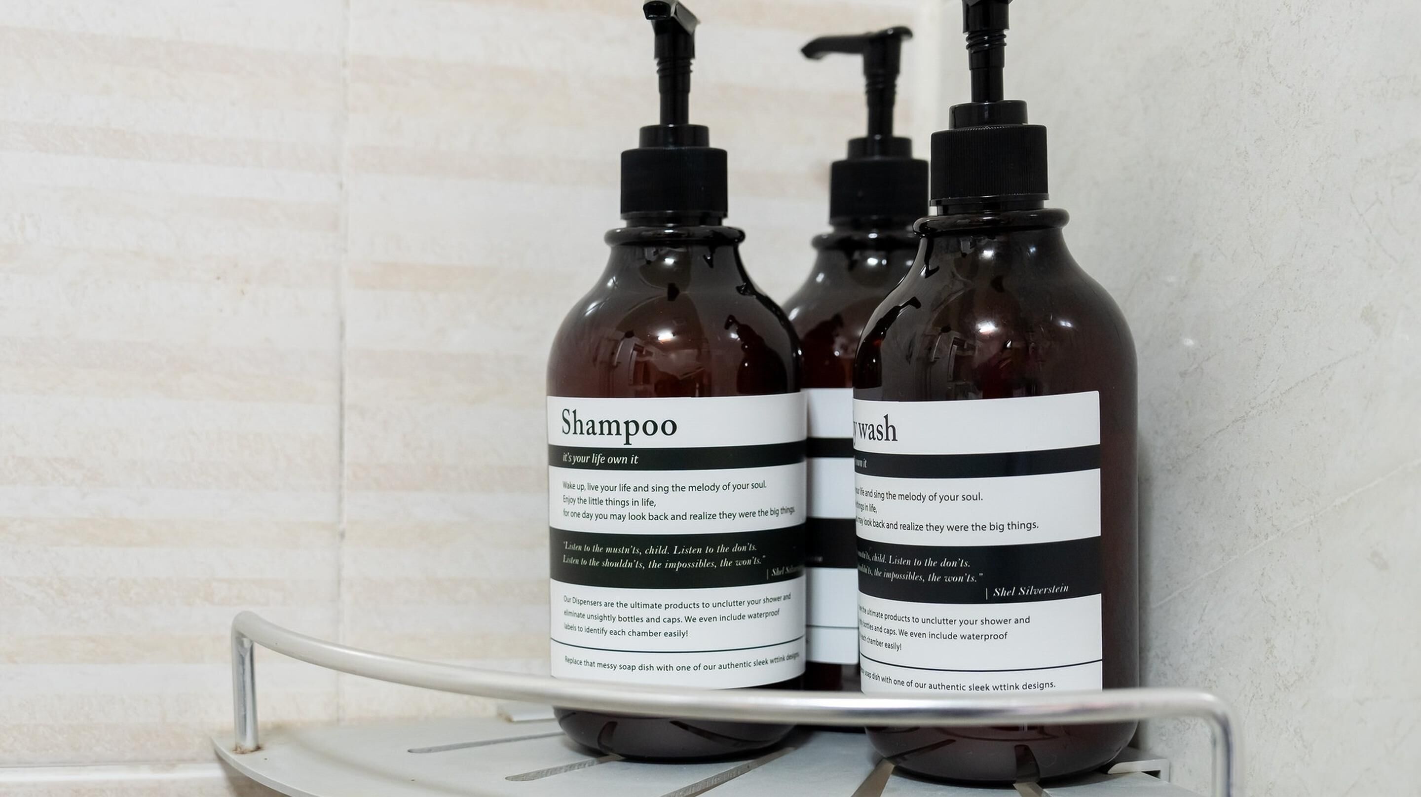 Deux bouteilles de shampoing et une bouteille de gel douche sur une étagère blanche.