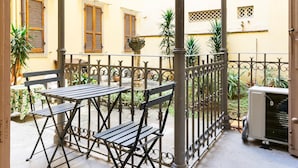 A courtyard with a metal table and chairs, a potted plant, and a building with wooden shutters. - Venezia Double in Firenze (Florence)