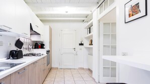 A modern kitchen with white cabinetry, a gas stove, and a coffee maker. - Venezia Double in Firenze (Florence)