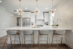 A modern kitchen with a large island, stainless steel appliances, and gold bar stools. - 4 blocks to The Riverwalk Luxe 3BR 3BA with Tropical Courtyard & Balcony (Tampa)
