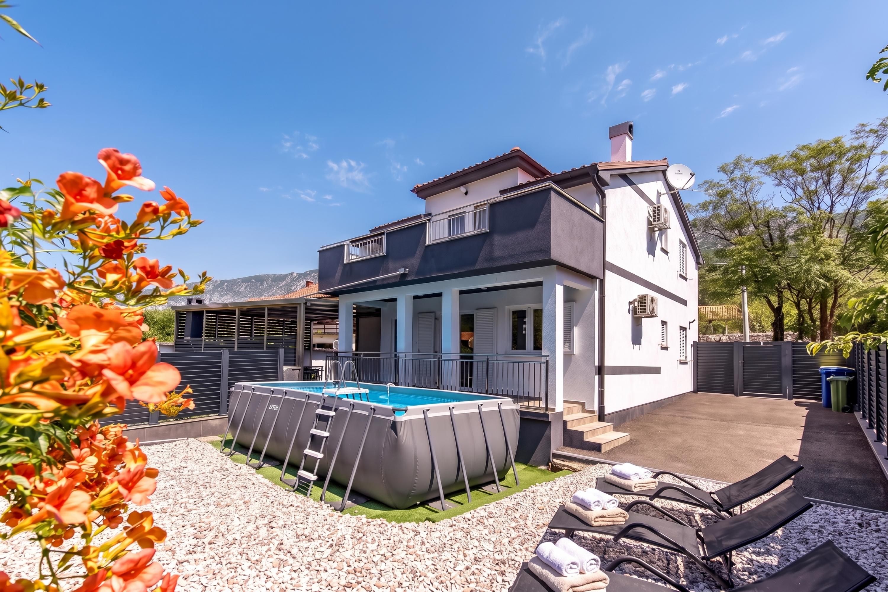 A two-story house with a swimming pool, outdoor seating, and a covered patio area.