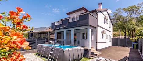 A two-story house with a swimming pool, outdoor seating, and a covered patio area.