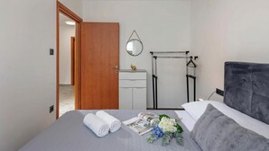 A bedroom with a bed, a wooden door, a white dresser, a mirror, a towel rack, and a window. - Pool House Beba Tribalj Lake (Vinodol)