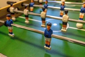 Ein Detailbild eines Kicker-Tisches mit Spielfiguren in blauer und weißer Uniform.