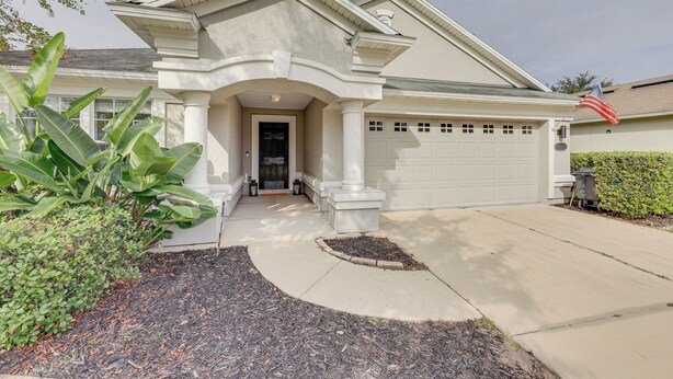 A residential house with a front porch, a garage, and a flag. - Private Patio + Lake View: Fruit Cove Home (St. Johns)