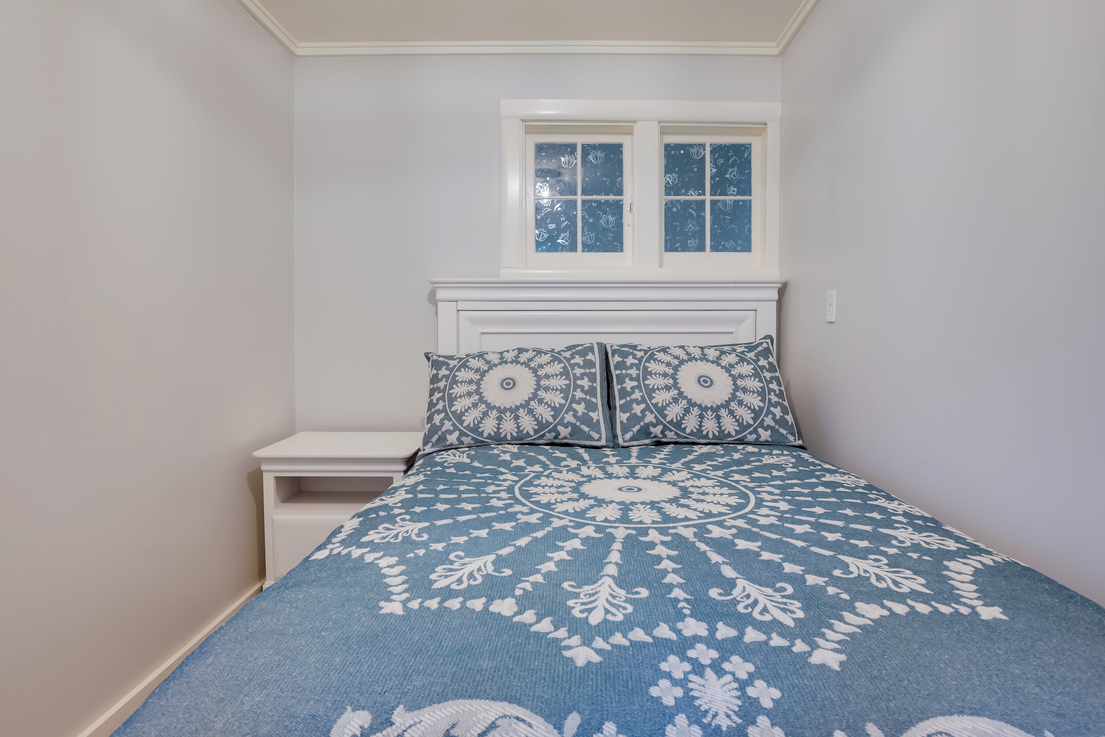 Una camera da letto con un letto, un comodino e una finestra.