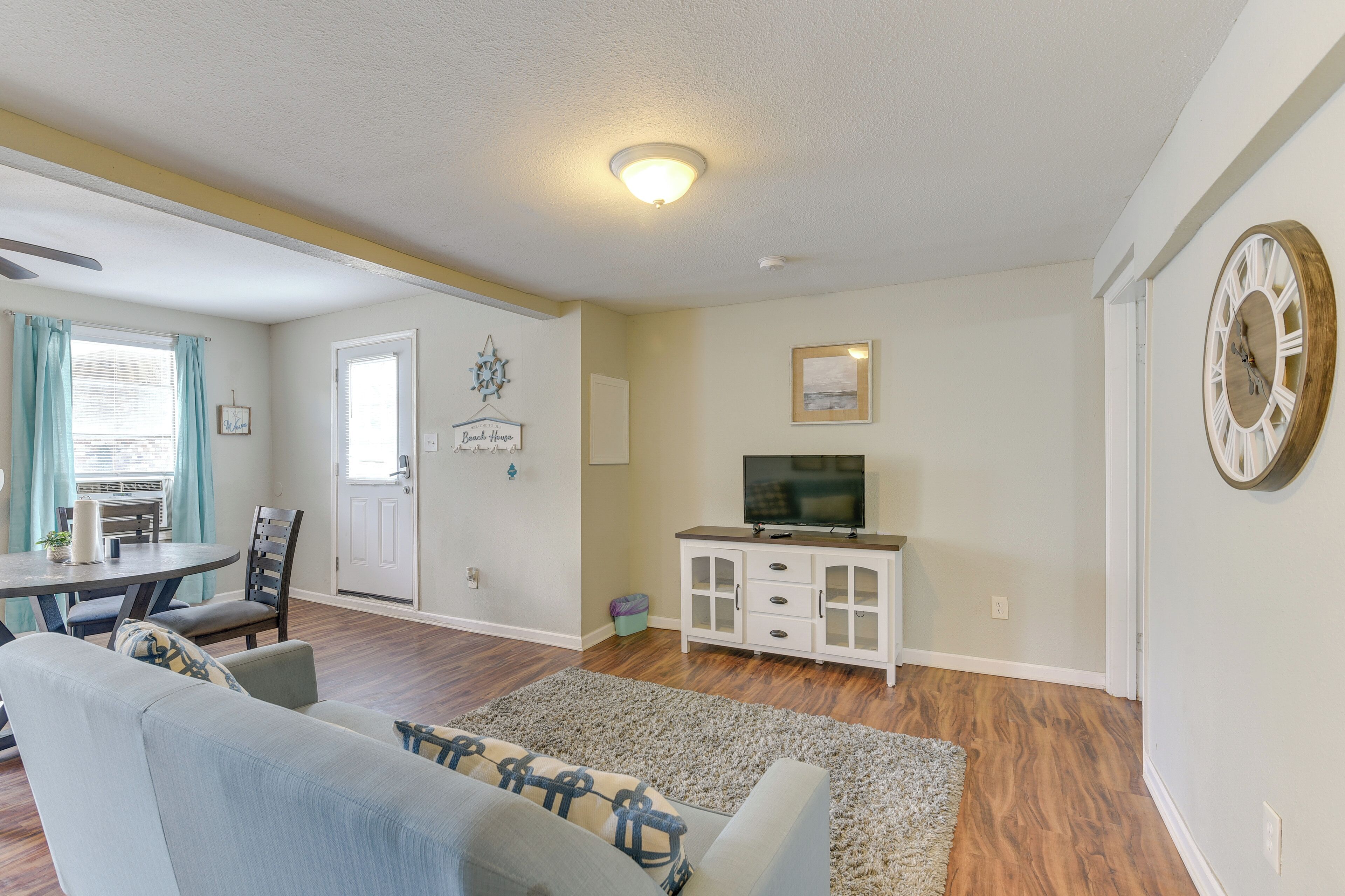 A living room with a sofa, TV stand, and dining area.