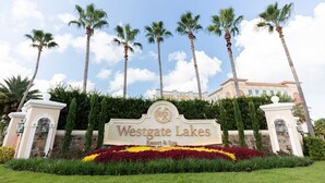 A sign for Westgate Lakes Resort & Spa with palm trees and a well-maintained garden in the foreground.