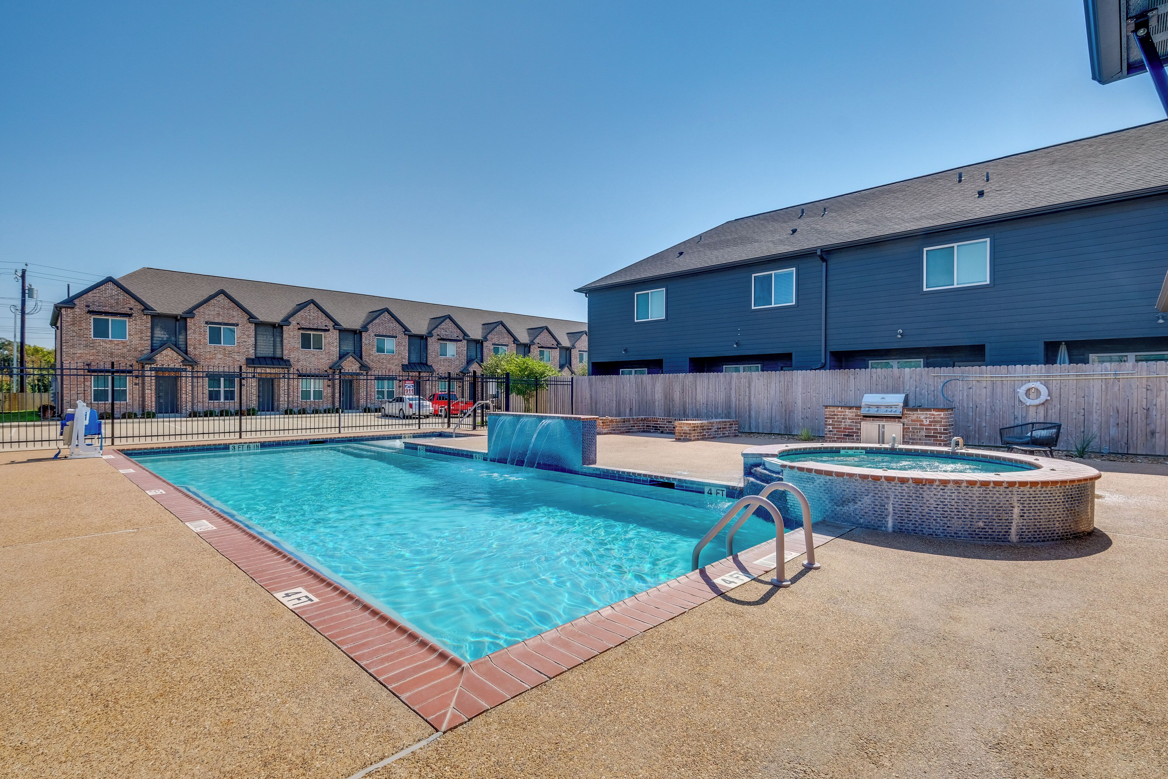 Ein Schwimmbecken mit Sprungbrett, Whirlpool und Grillplatz.