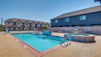 Ein Schwimmbecken mit Sprungbrett, Whirlpool und Grillplatz.