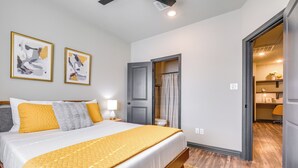 Een slaapkamer met een bed, een deur en een zichtbare badkamer door een geopende deur.