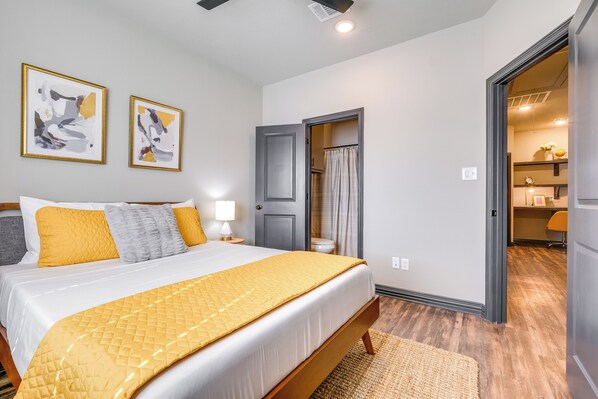 A bedroom with a bed, a door, and a bathroom visible through an open door. - 'corner Hideaway' 3 Mi to Texas A & M (College Station)