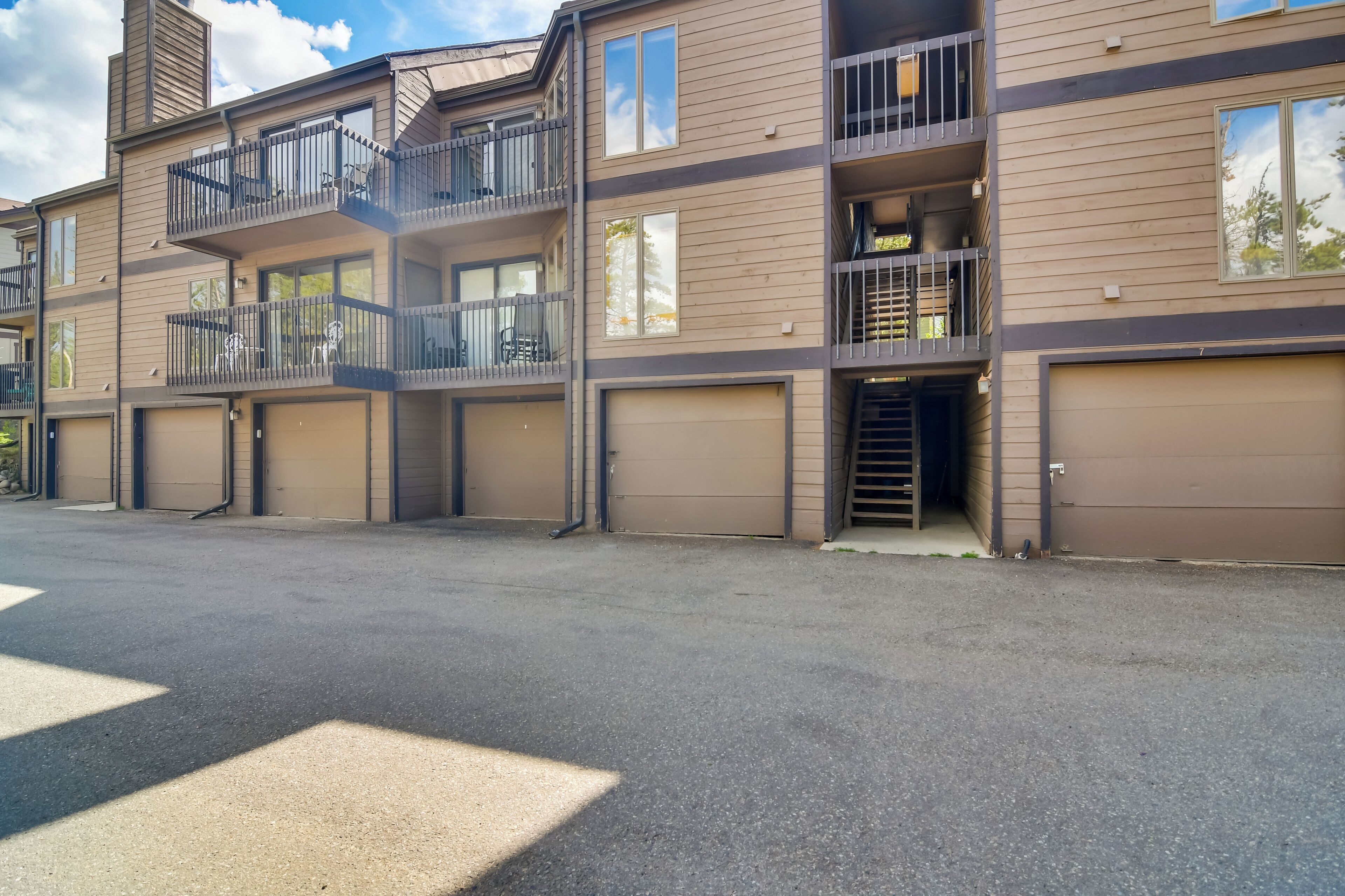 A multi-story residential building with balconies, garage doors, and a clear sky.
