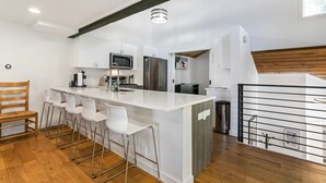 A modern kitchen with white cabinetry, stainless steel appliances, and a central island with bar stools. - 98 Ridgepoint 4 Bedroom Condo by RedAwning (Avon)