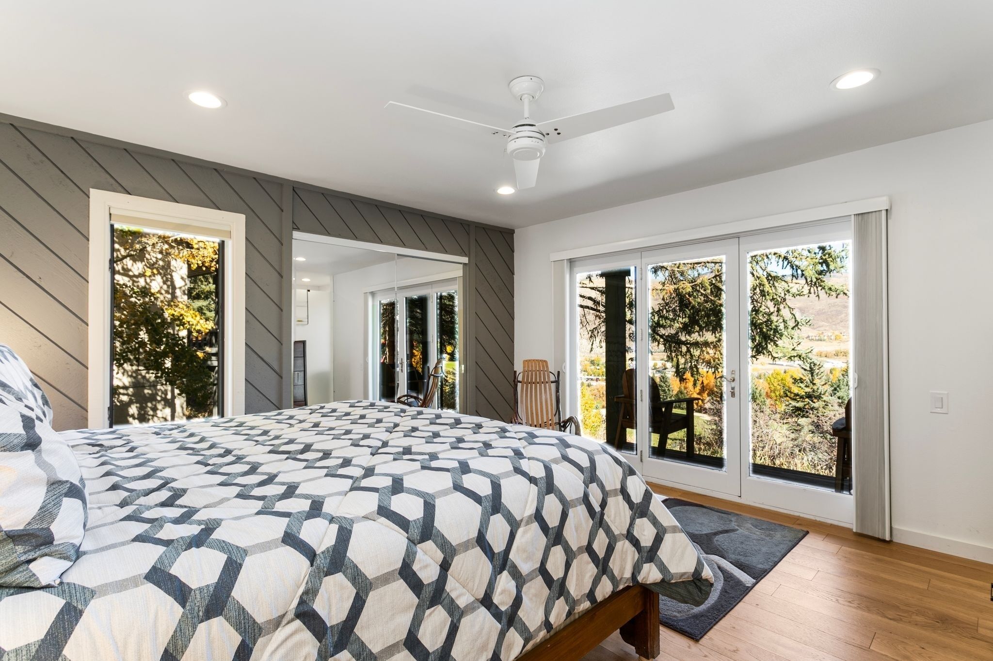 A bedroom with a large bed, a ceiling fan, and a view through the sliding glass doors.