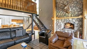 A cozy living area with a stone fireplace, leather sofas, and a wooden staircase. - 98 Ridgepoint 4 Bedroom Condo by RedAwning (Avon)