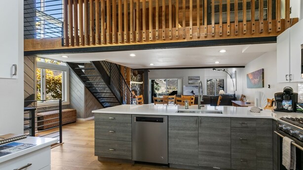 A modern kitchen with a large island, wooden staircase, and a view of the outdoors. - 98 Ridgepoint 4 Bedroom Condo by RedAwning (Avon)