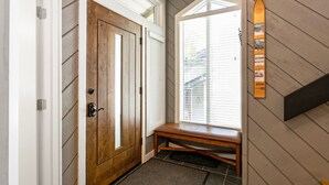A wooden door with a bench, a window with blinds, and a wall-mounted sign. - 98 Ridgepoint 4 Bedroom Condo by RedAwning (Avon)