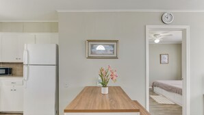 A modern kitchen with a white refrigerator, a microwave, and a wooden dining table with a potted plant. - ~ 1 Mi to the Strand: Central Unit in Galveston! (Galveston)