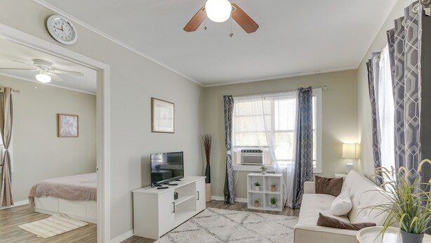 A well-lit living room with a TV, sofa, and a ceiling fan. - ~ 1 Mi to the Strand: Central Unit in Galveston! (Galveston)