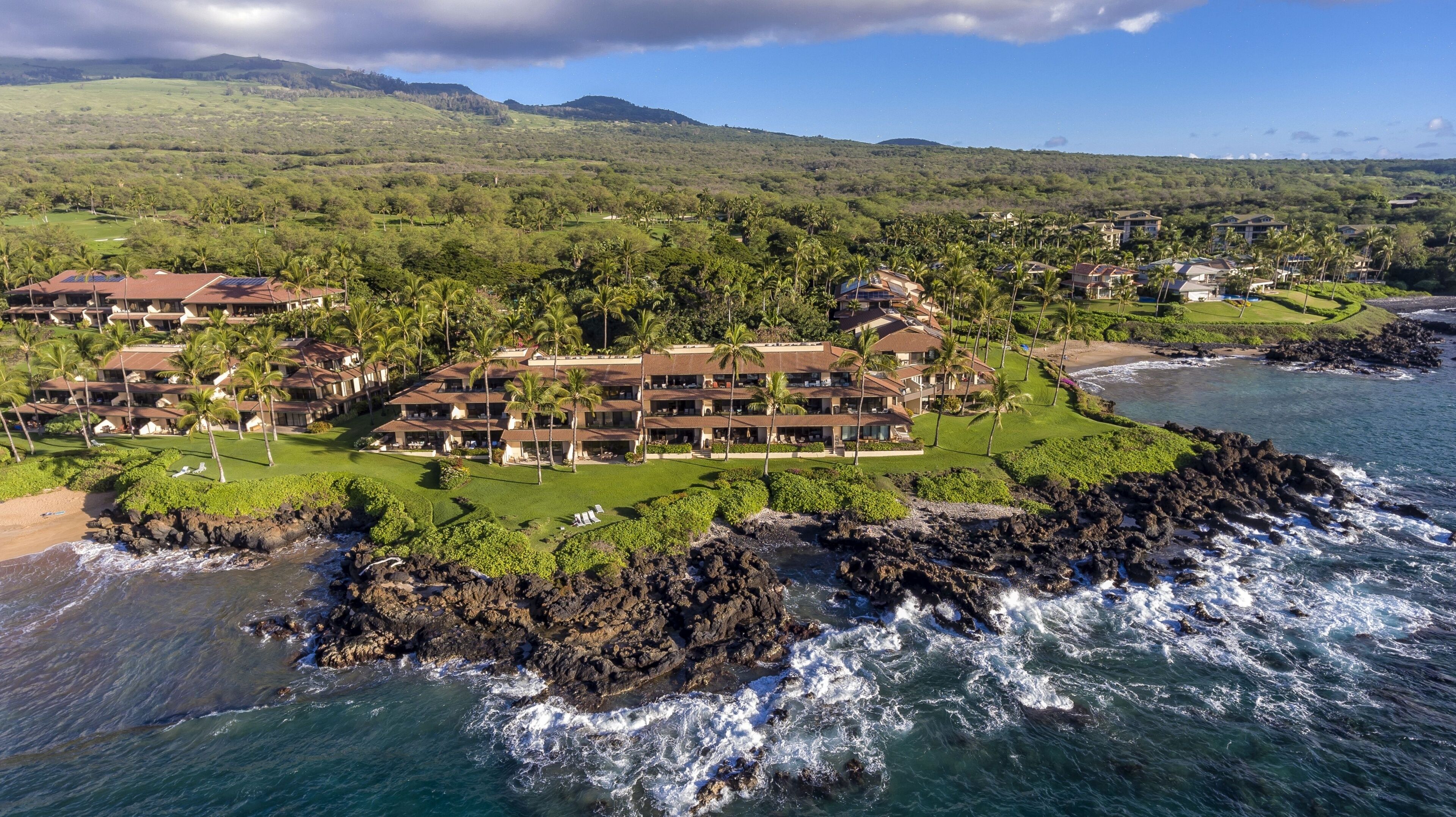 Um resort costeiro com vários edifícios, um trecho de costa rochosa e vista para o oceano.