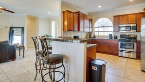 A kitchen with wooden cabinets, a stainless steel refrigerator, and a built-in oven. - Lanai + Pool: Family-friendly Home in Cape Coral (Cape Coral)