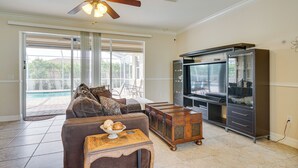A living room with a brown sofa, wooden coffee table, and a TV stand. - Lanai + Pool: Family-friendly Home in Cape Coral (Cape Coral)