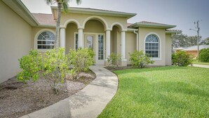 A two-story house with a curved driveway, a palm tree, and a well-maintained lawn. - Lanai + Pool: Family-friendly Home in Cape Coral (Cape Coral)