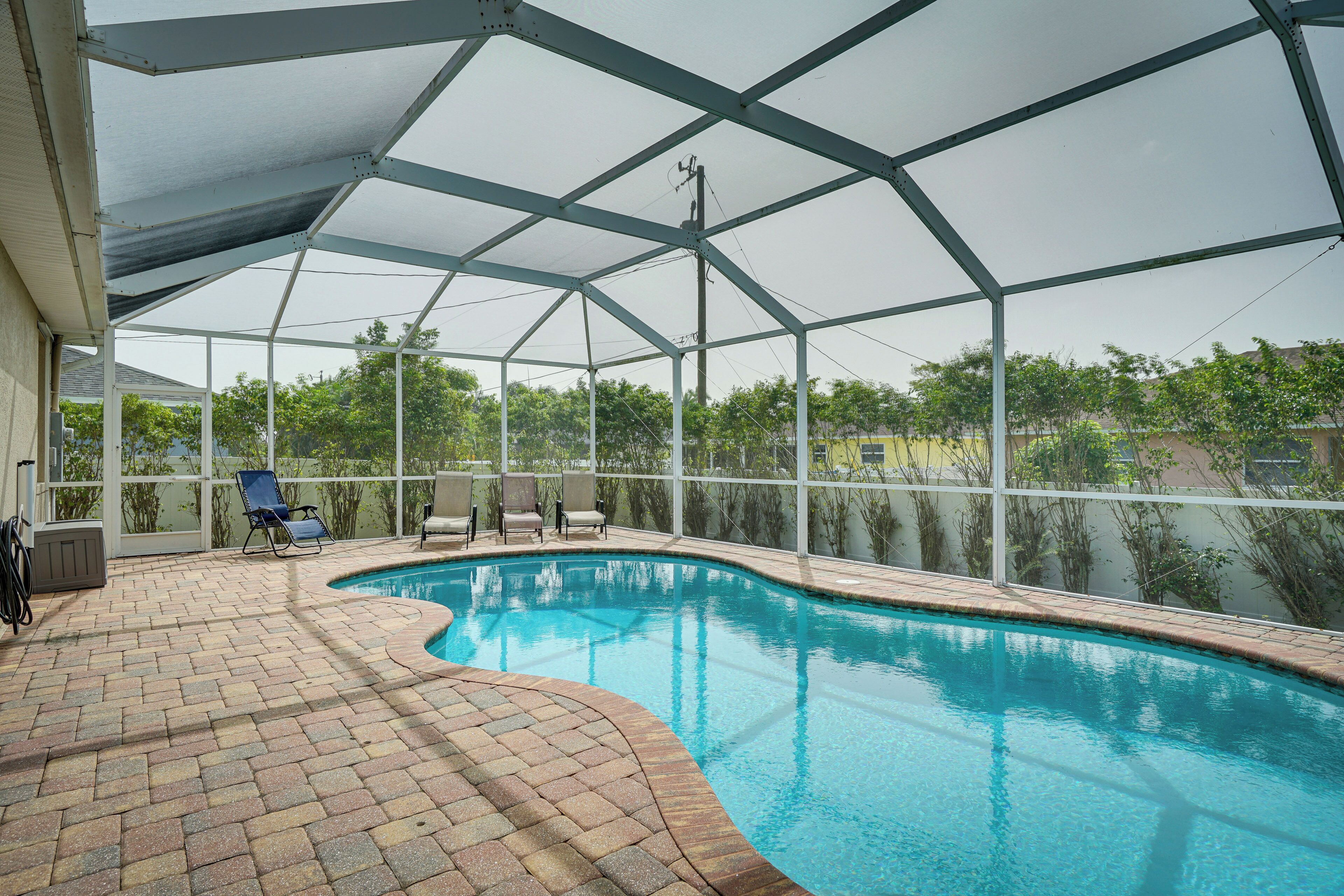 An indoor swimming pool with a brick floor and a covered area with chairs.