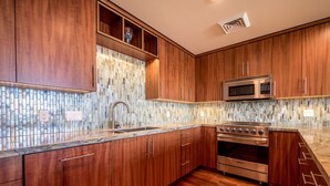 Een moderne keuken met houten kastjes, een roestvrijstalen oven en een glazen spatwand.