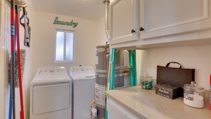 Ένα πλυσταριό με δύο πλυντήρια ρούχων, ένα στεγνωτήριο και ένα μικρό παράθυρο.