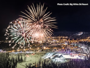 A resort with multiple buildings, a parking area, and a snowy landscape. - Front Row for the Fireworks in Modern Happy Valley Executive TH (Beaverdell)