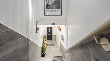 A modern hotel lobby with a staircase, a black door, and a framed photo on the wall.