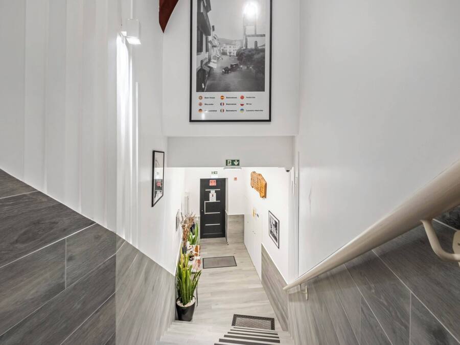 A modern hotel lobby with a staircase, a black door, and a framed photo on the wall.