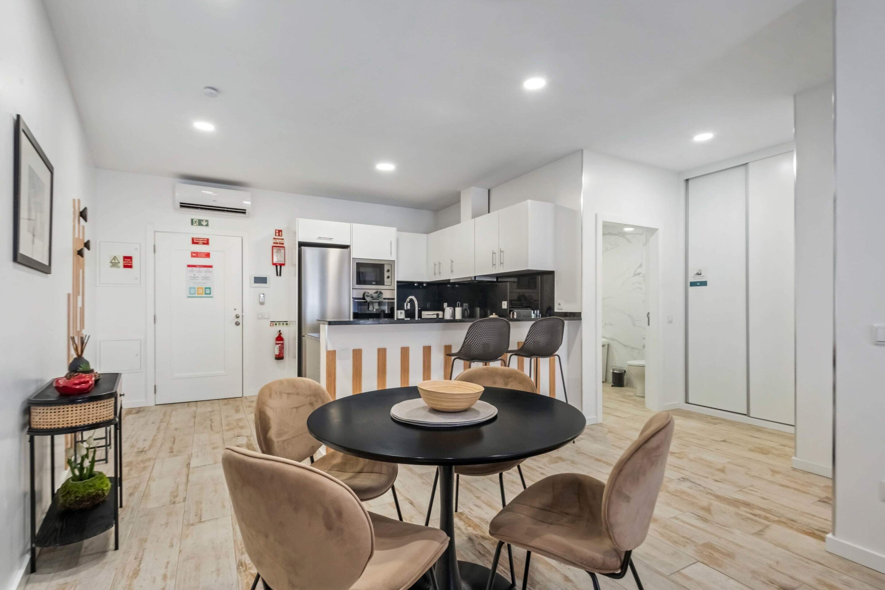 Una cocina moderna con armarios blancos, una encimera negra y una mesa redonda con cuatro sillas.