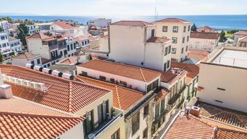 A coastal town with terracotta-tiled rooftops and white buildings, featuring a clear view of the sea.