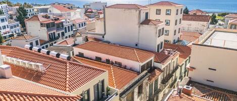 A coastal town with terracotta-tiled rooftops and white buildings, featuring a clear view of the sea.