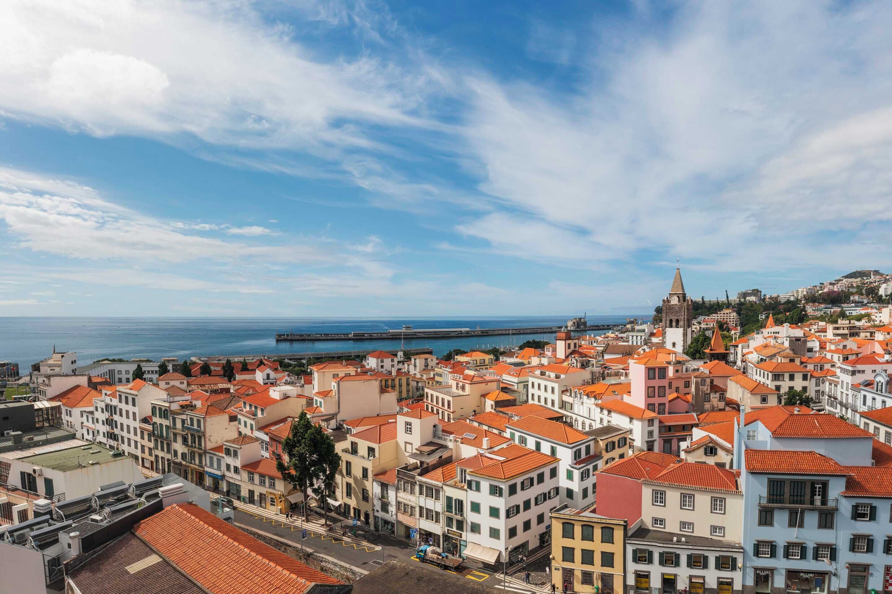 A coastal cityscape with historic buildings and a prominent tower.