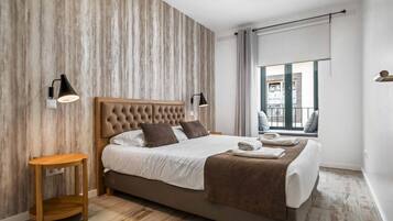 A modern bedroom with a large bed, wooden side tables, and a view of the outdoors.