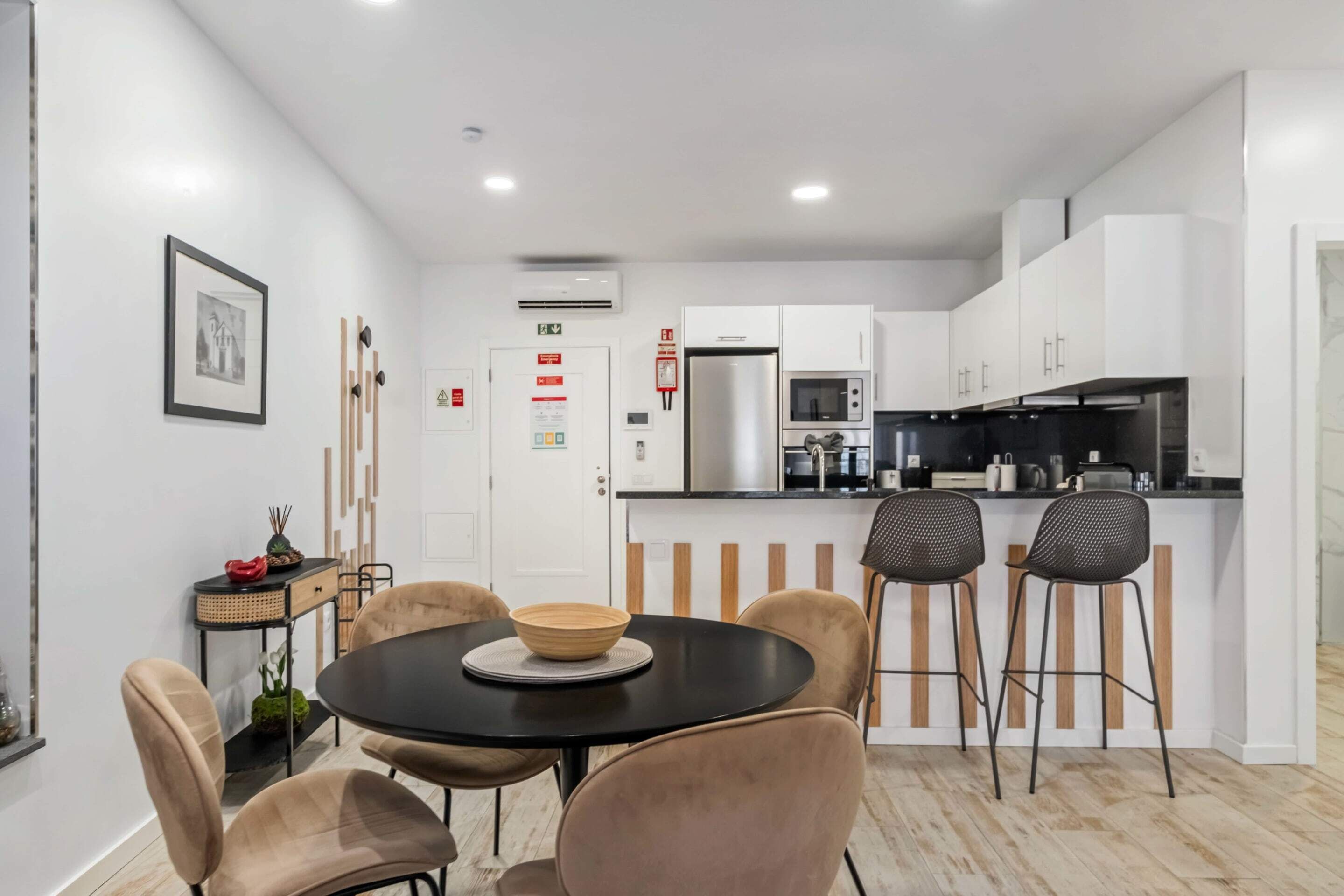 A modern kitchen with white cabinets, a black countertop, and a dining area with a round table and chairs.