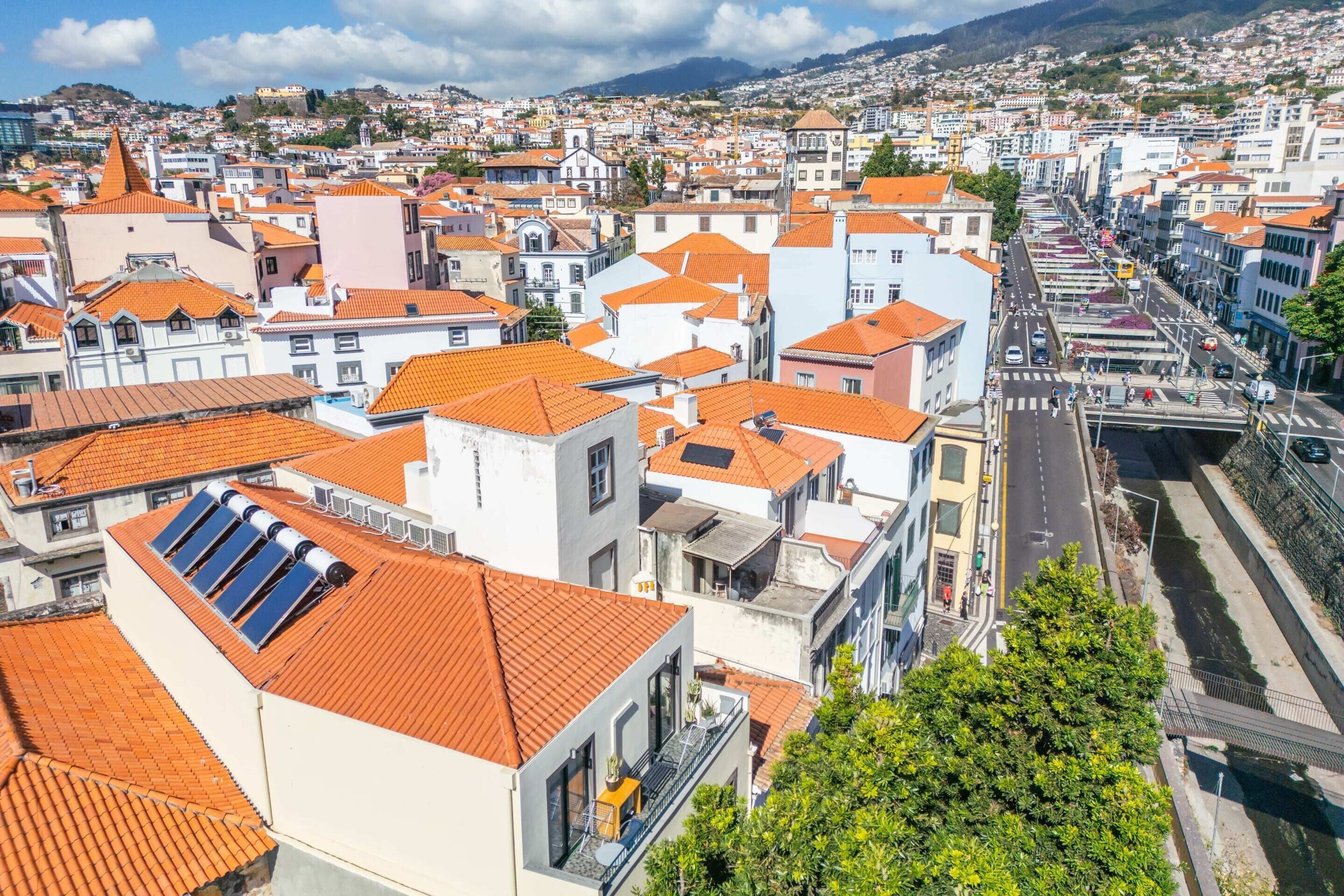 Un paysage urbain présentant une variété de bâtiments, notamment des immeubles résidentiels et commerciaux, tous coiffés de toits recouverts de tuiles rouges.