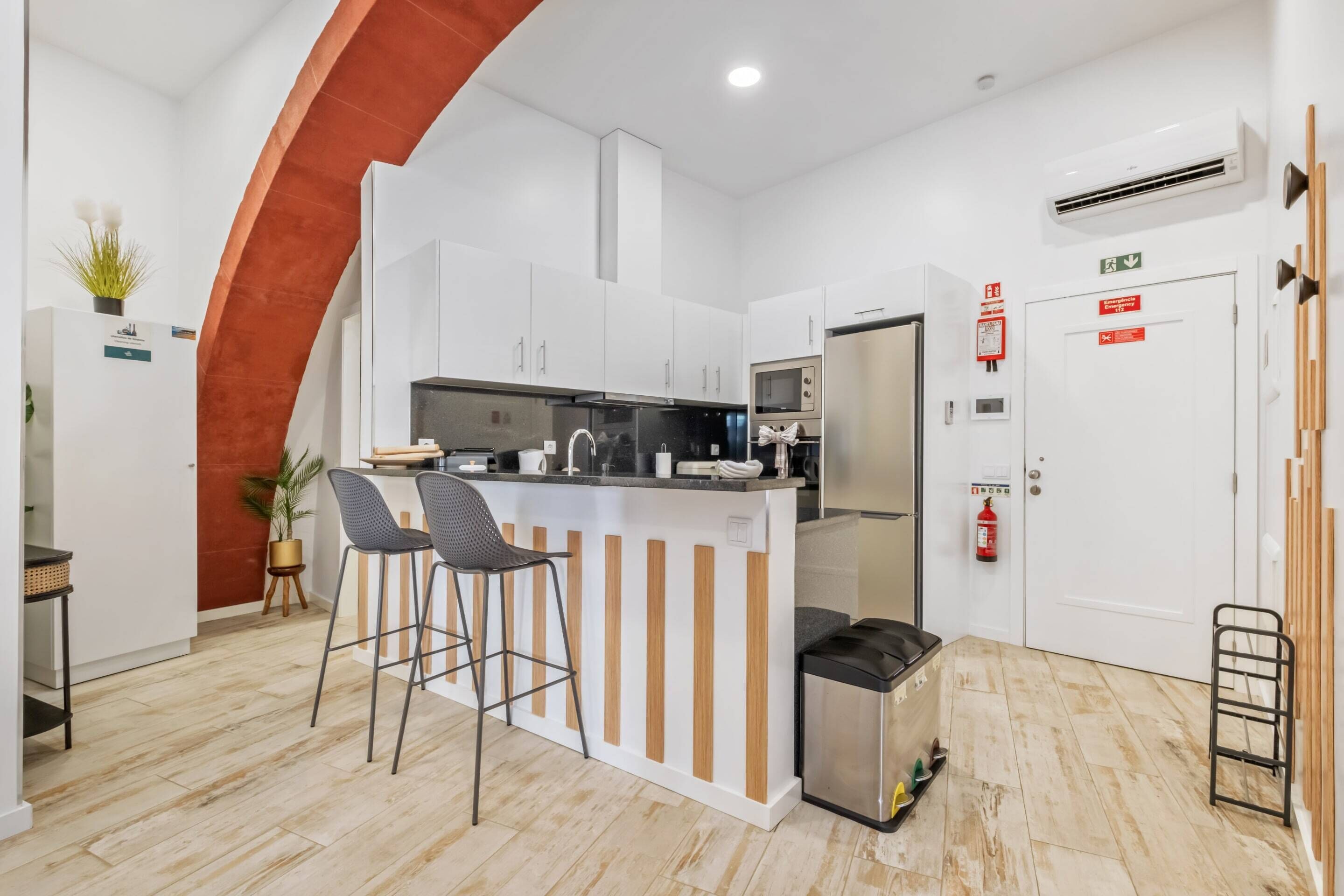 Een moderne keuken met witte kasten, een centraal eiland met barkrukken, een magnetron en een koelkast.